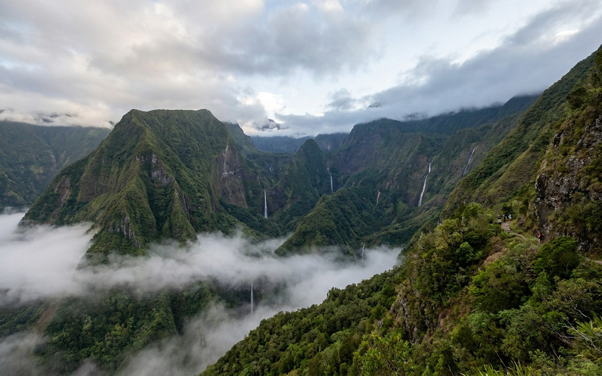 a vast collapsed volcanic amphitheatre of green ridges and waterfalls with cloud pooling in the cirque floor at Réunion — original Triple VIP destination visual.