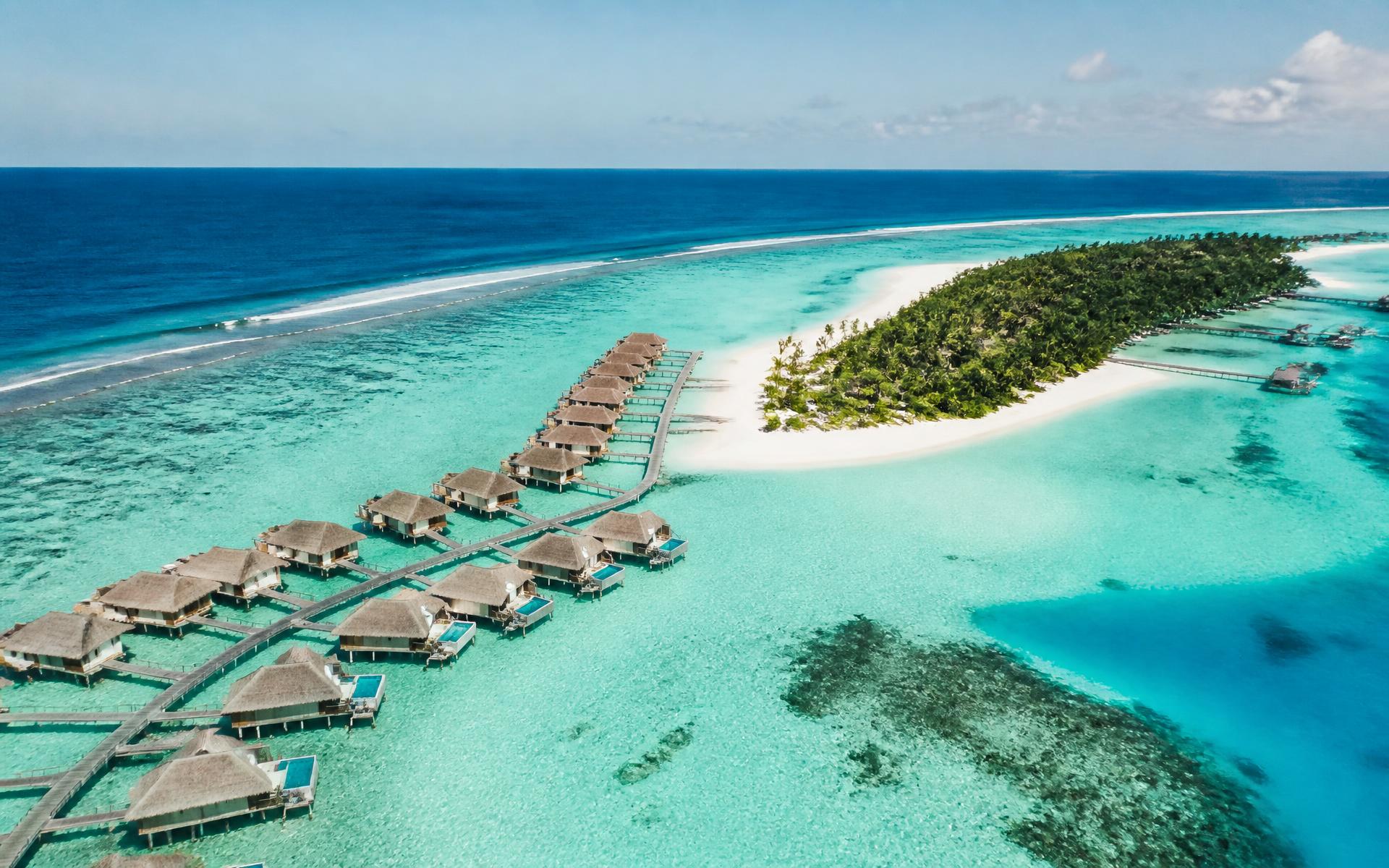 Overwater villas on stilts above a turquoise reef lagoon in the Maldives