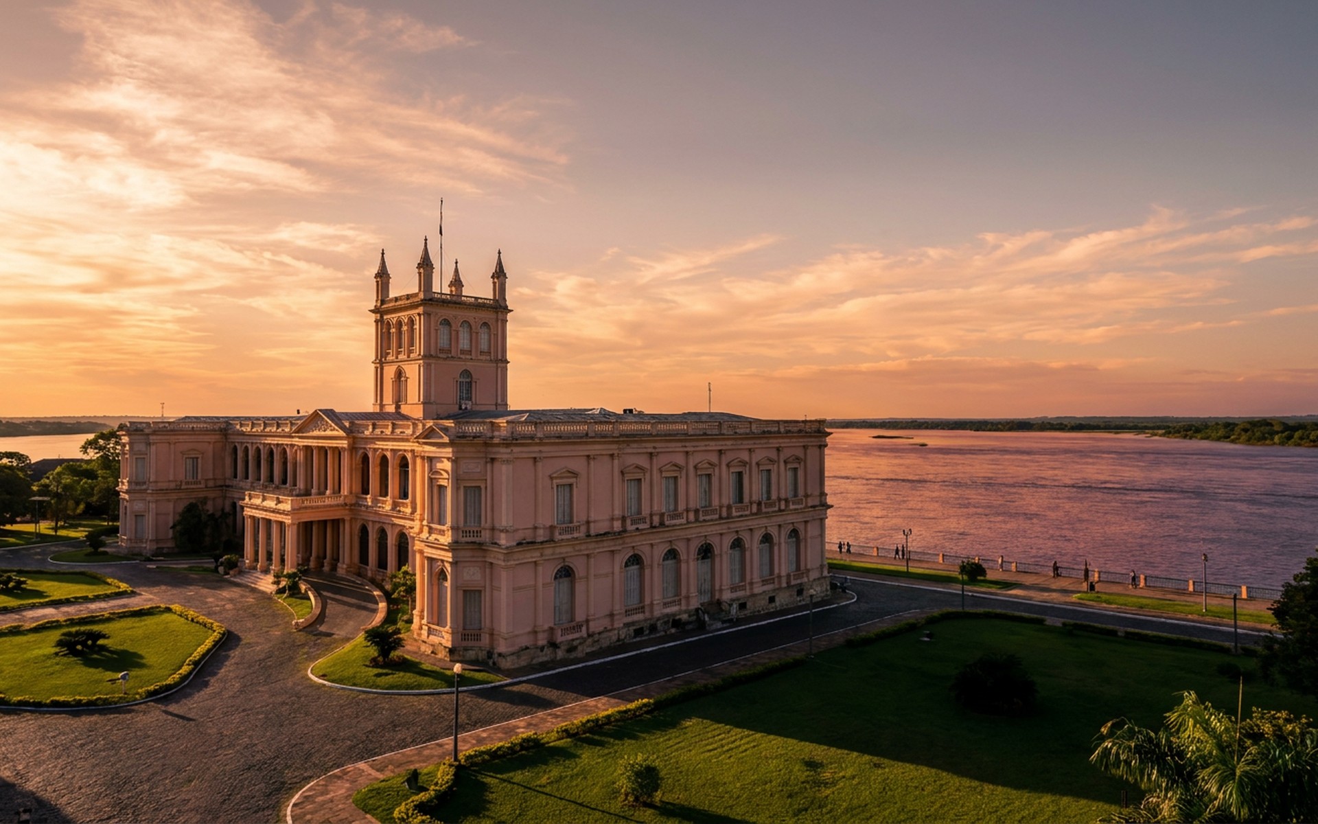 Vibrant sunset casting long shadows over the historic Palacio de los López in Asunción, with the Paraguay River in the background during late spring. at Asunción & Jesuit Missions, Paraguay — original Triple VIP destination visual.