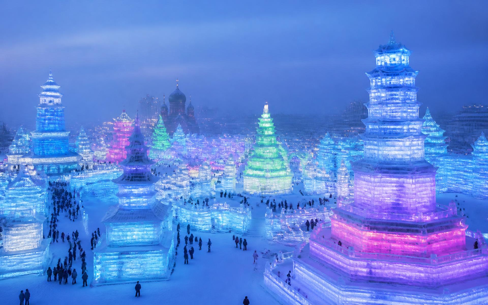 monumental translucent ice-block architecture lit from within in saturated colour across a snow plain at Harbin Ice Festival, China, in blue hour light — original Triple VIP destination visual.