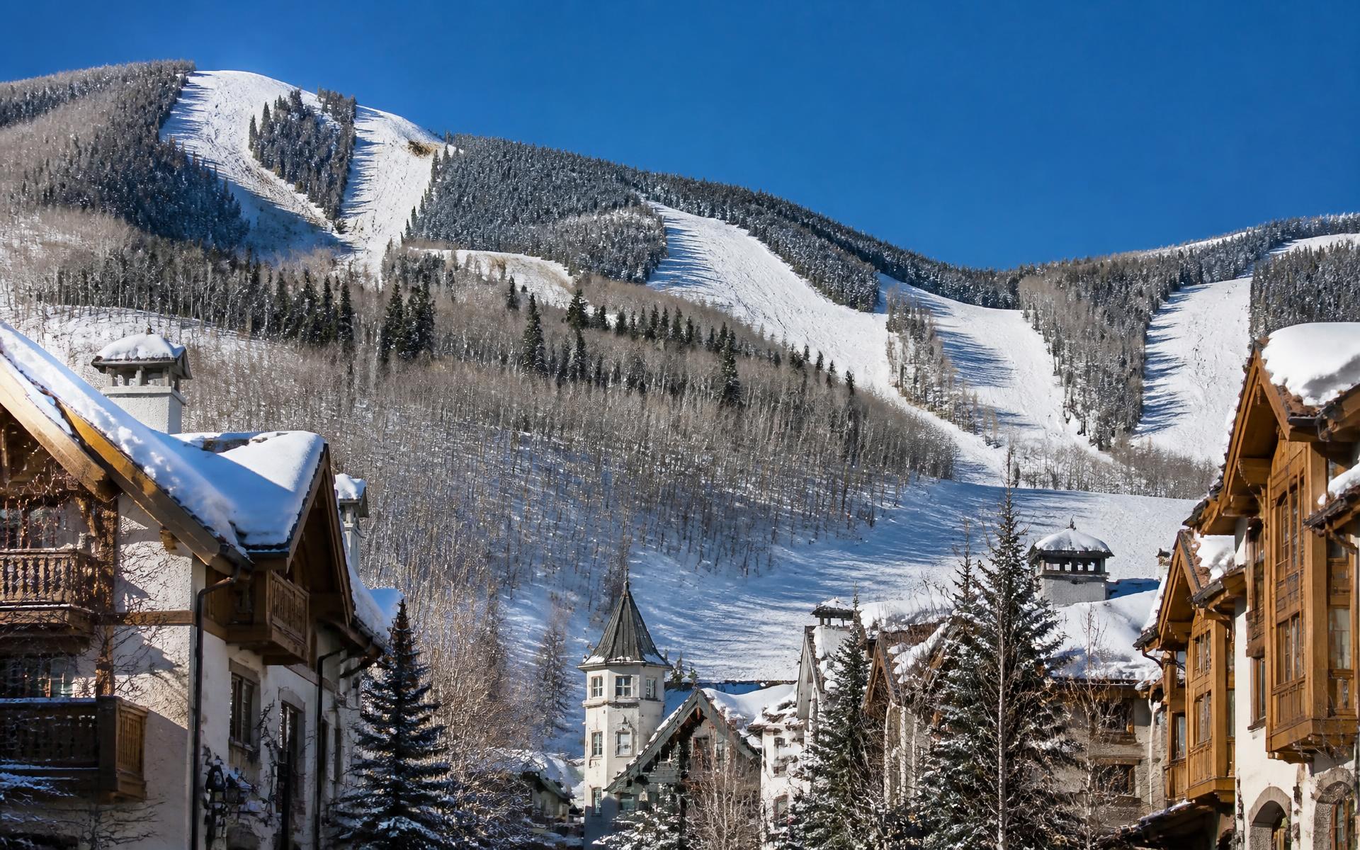 Snow-covered alpine village chalets below groomed ski runs at Vail, Colorado
