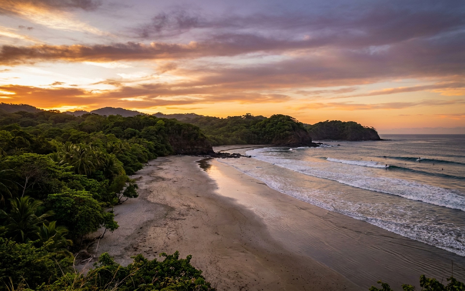 Vast sandy beach of Playa Guiones in Nosara, framed by lush tropical jungle, with surfers riding Pacific waves under a vibrant sunset. at Nosara, Costa Rica — original Triple VIP destination visual.