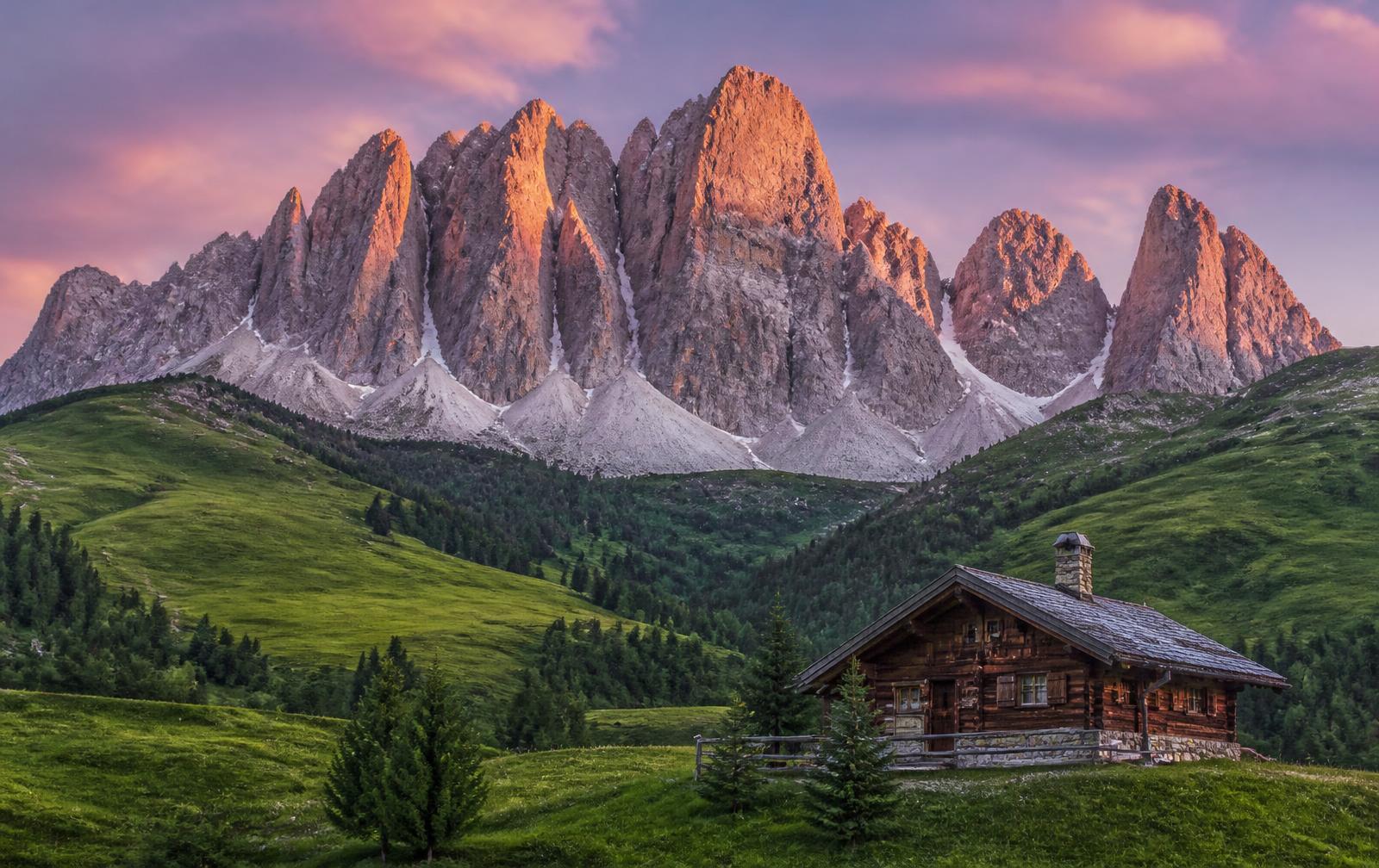 Alpenglow on the limestone spires of the Dolomites above alpine meadows, Italy