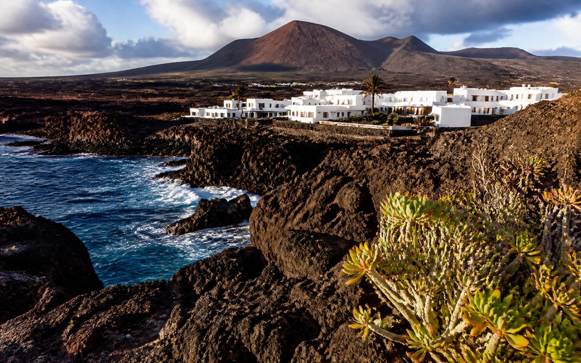 black volcanic craters and lava fields meeting the Atlantic coast at Lanzarote, Canary Islands — original Triple VIP destination visual.