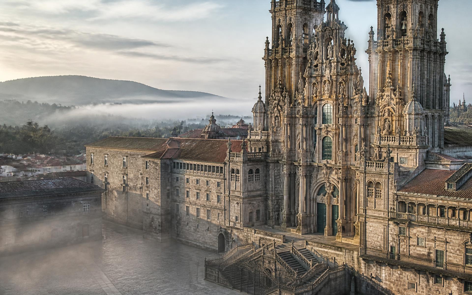 granite spires of a cathedral above a rain-washed old-town square at Santiago de Compostela, Galicia, Spain — original Triple VIP destination visual.