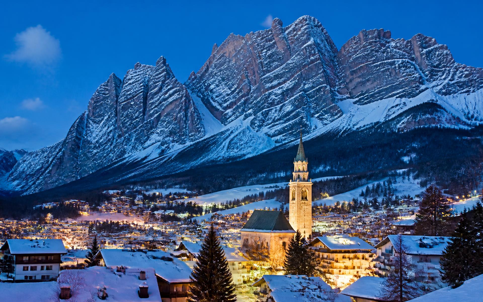 a Dolomite valley town beneath jagged pale limestone peaks at Cortina d'Ampezzo, Italy — original Triple VIP destination visual.