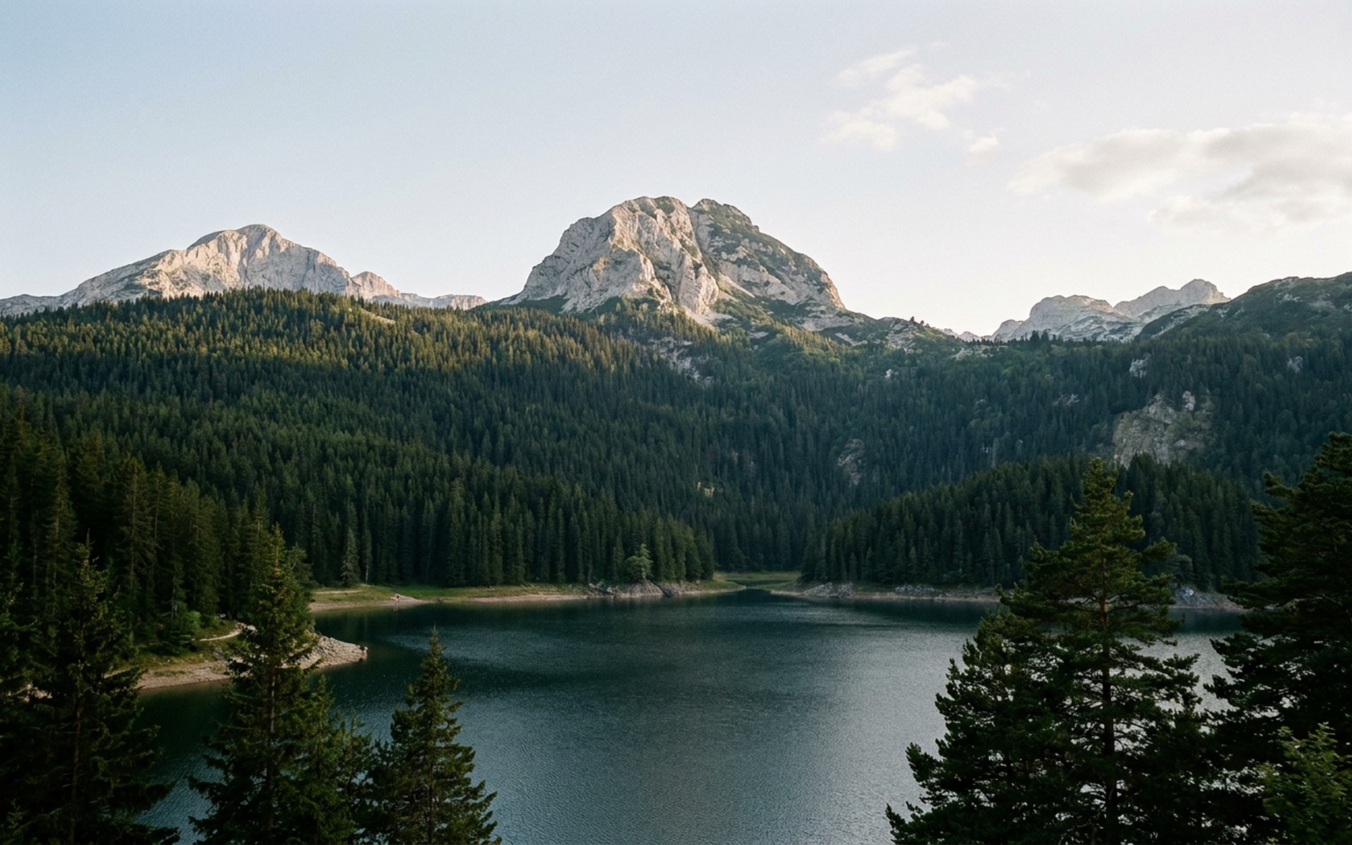 a glacial lake ringed by black pine forest below sharp limestone peaks at Durmitor, Montenegro — original Triple VIP destination visual.