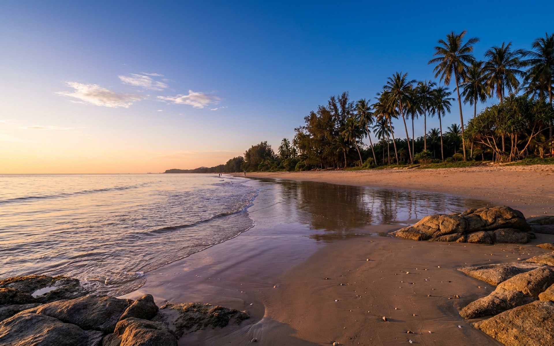 Tranquil sunset over the Andaman Sea at Khao Lak, with golden light reflecting on calm waves and palm trees silhouetted along the sandy beach. at Khao Lak, Thailand — original Triple VIP destination visual.