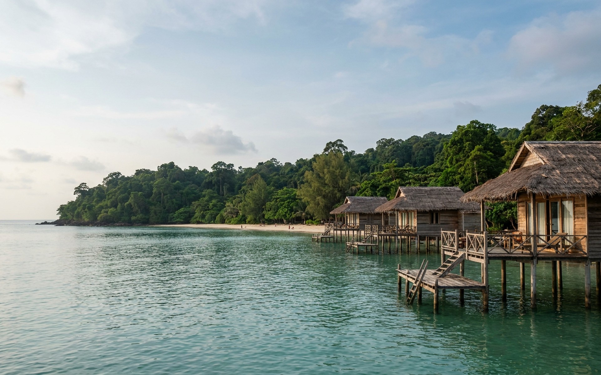 Overwater bungalows extending into the clear turquoise waters of Saracen Bay on Koh Rong Samloem, surrounded by untouched lush jungle. at Koh Rong Samloem, Cambodia — original Triple VIP destination visual.