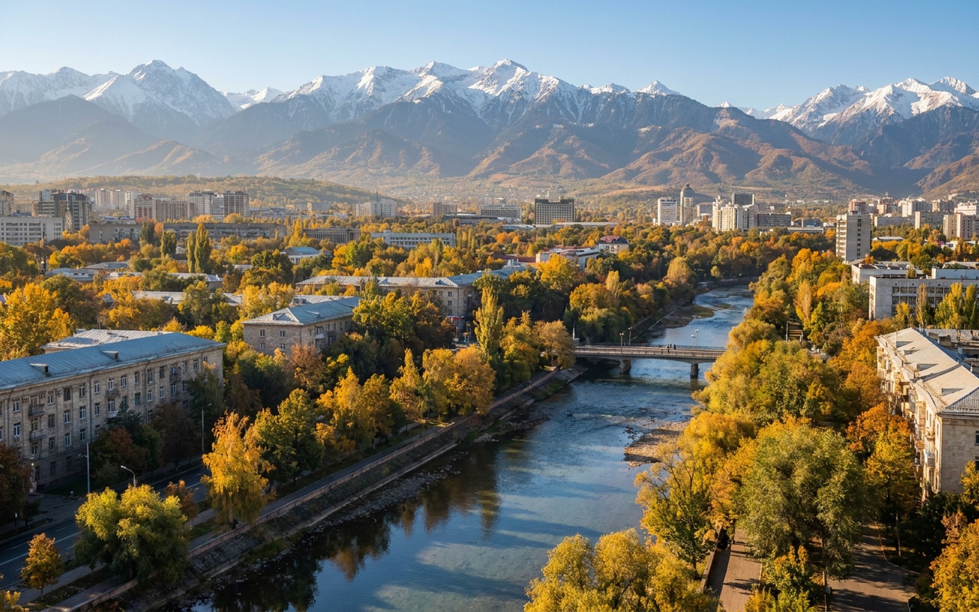 a green tree-lined city below the snow wall of the Tien Shan range in clear autumn light at Almaty, Kazakhstan — original Triple VIP destination visual.