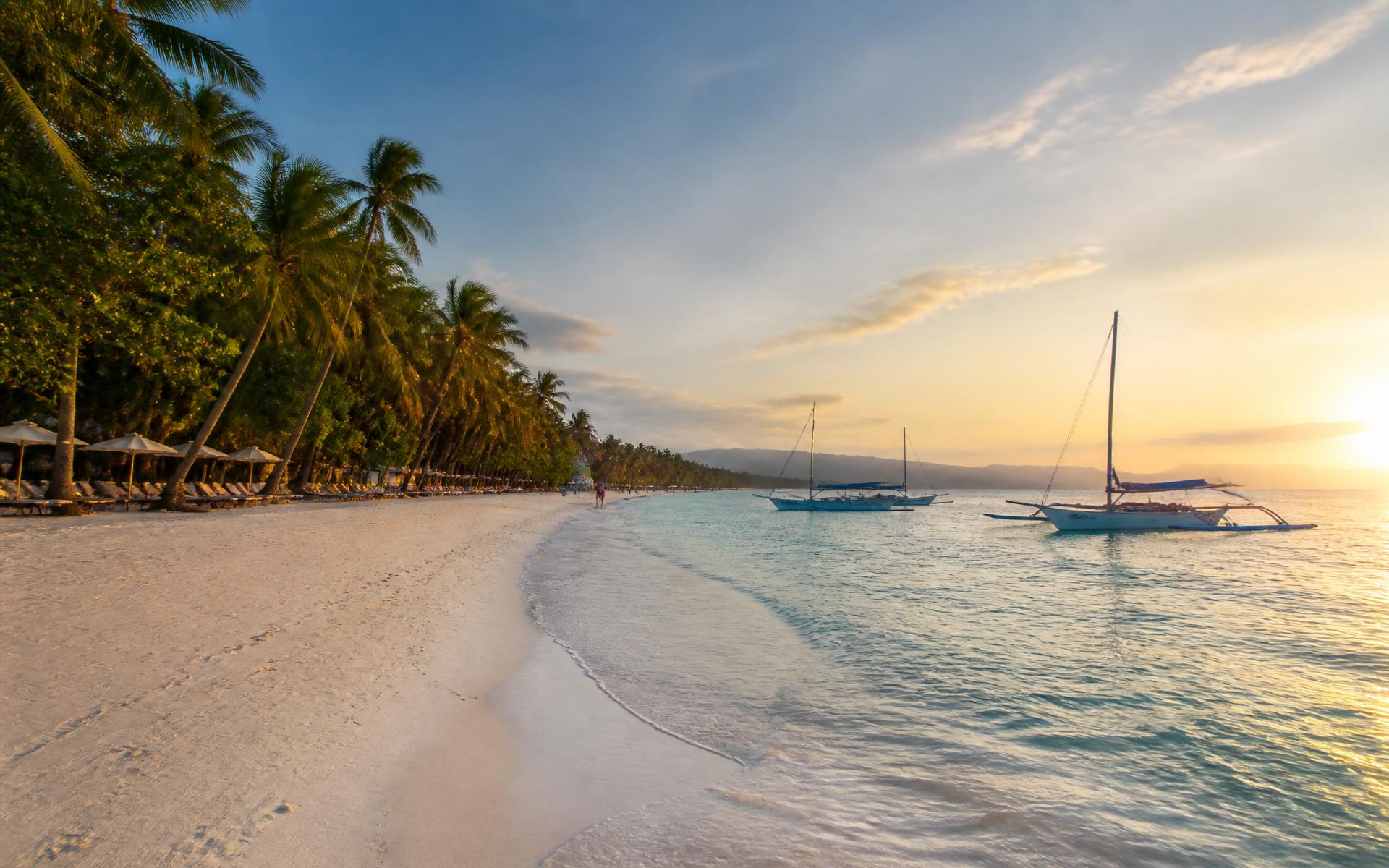 Palm-fringed white sand and shallow turquoise water on a tropical Philippine island