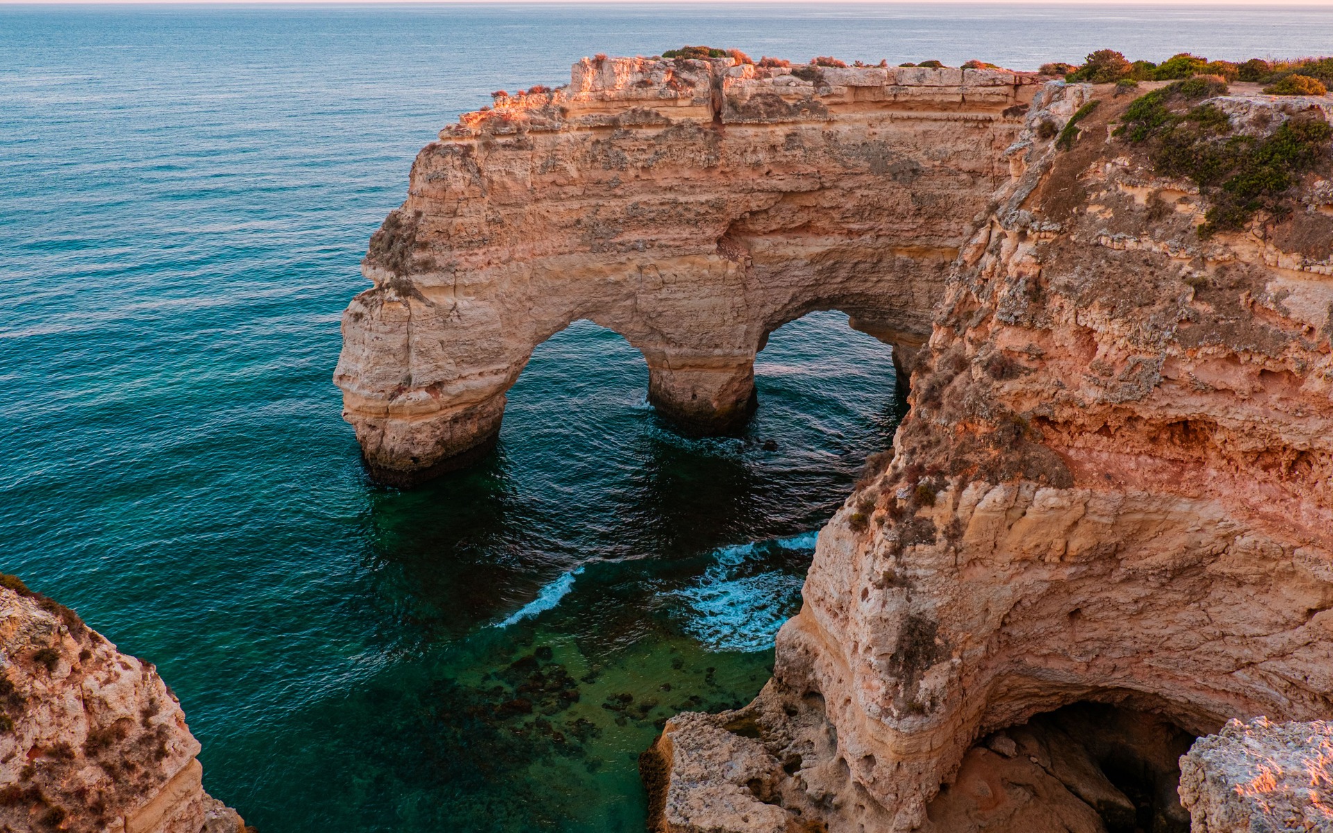 Natural sea arch and warm limestone cliffs on Portugal’s Algarve coast