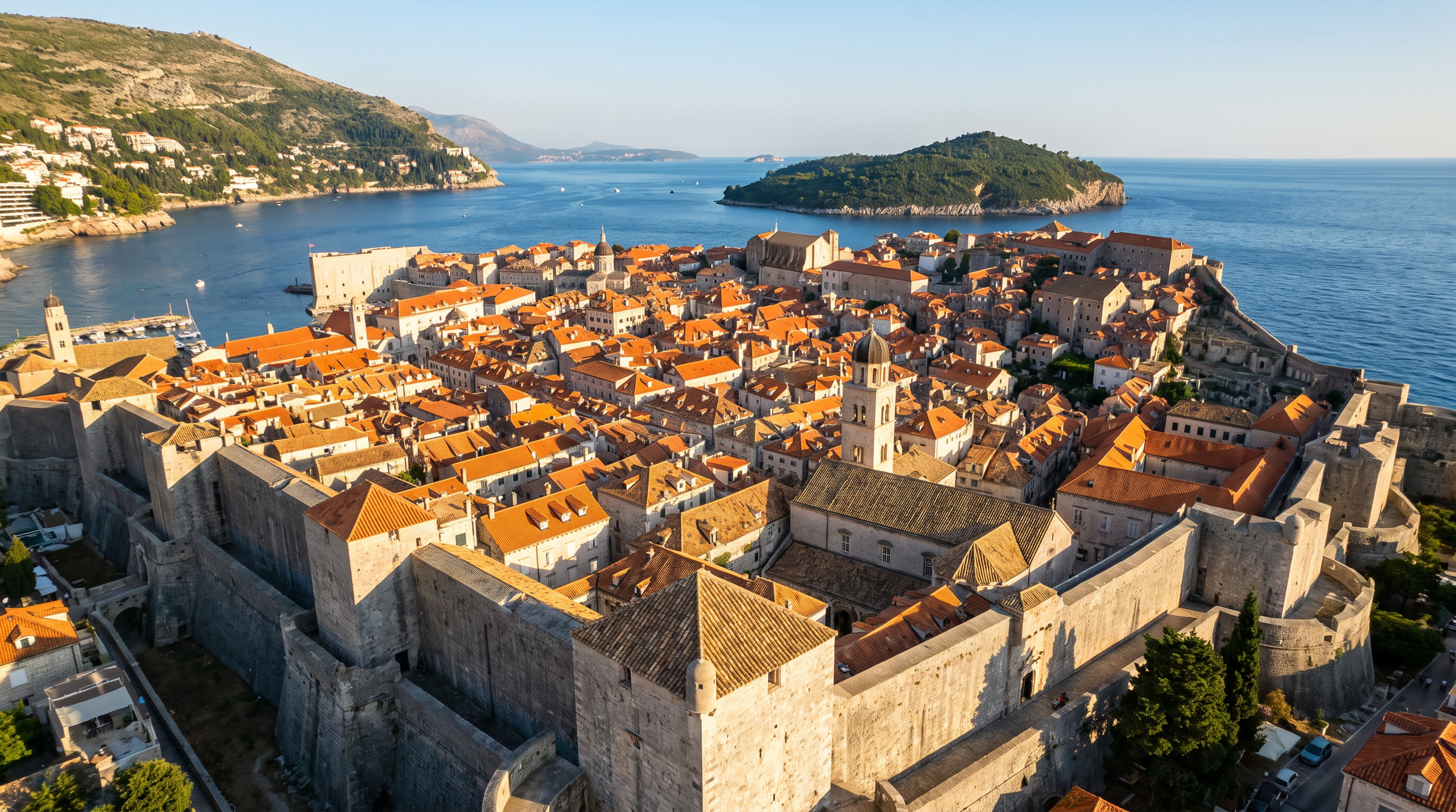 the walled old town's terracotta roofscape enclosed by stone ramparts on the Adriatic at Dubrovnik, Croatia, in late afternoon light — original Triple VIP destination visual.