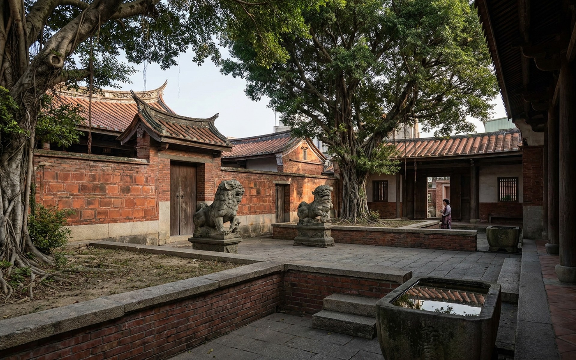 an old temple courtyard of red walls, swallowtail roofs and stone lions with banyan shade at Tainan, Taiwan — original Triple VIP destination visual.