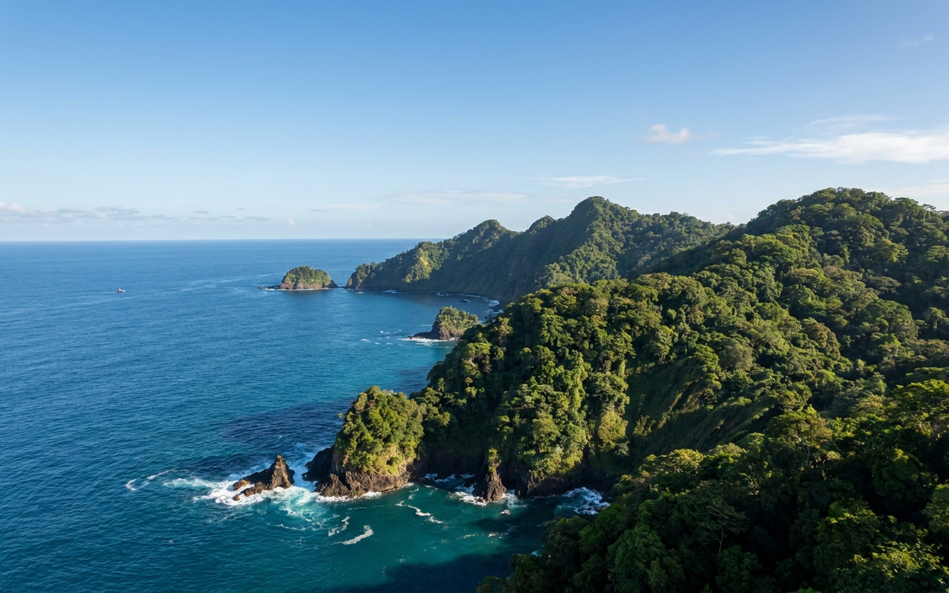 Lush, untouched tropical rainforest covering volcanic cliffs that drop dramatically into the Pacific Ocean, under a sunny sky. at Cocos Island, Costa Rica — original Triple VIP destination visual.
