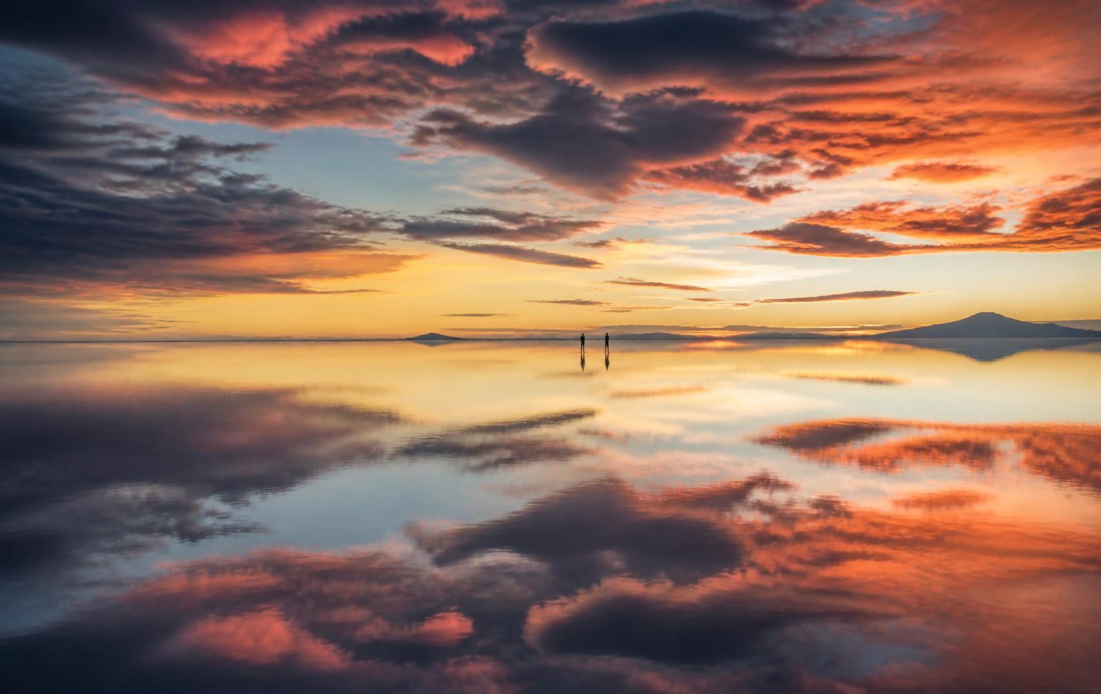 Mirror-like wet-season reflections across the Salar de Uyuni salt flat at sunset, Bolivia