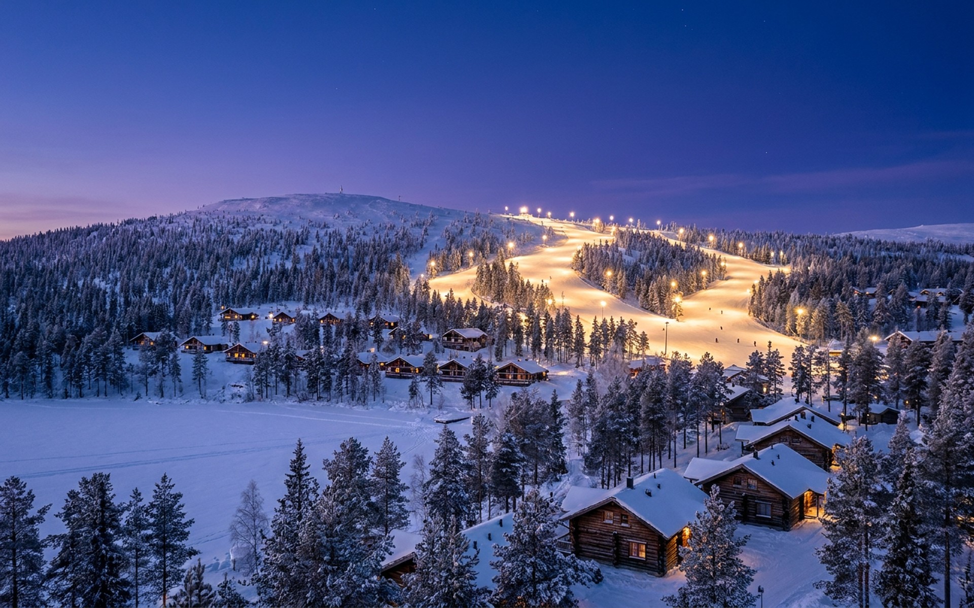 a low fell of snow-laden spruce with a floodlit ski slope and timber lodges under deep blue polar twilight at Levi, Finnish Lapland — original Triple VIP destination visual.