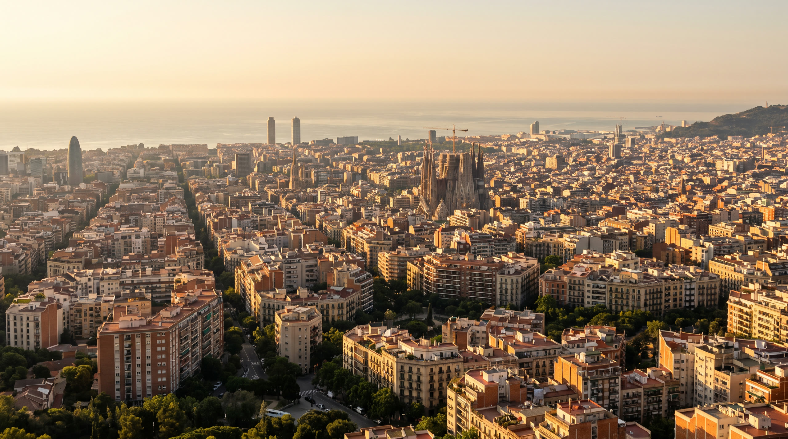 the Eixample grid's octagonal blocks running to the Mediterranean at Barcelona, Spain, in golden hour light — original Triple VIP destination visual.