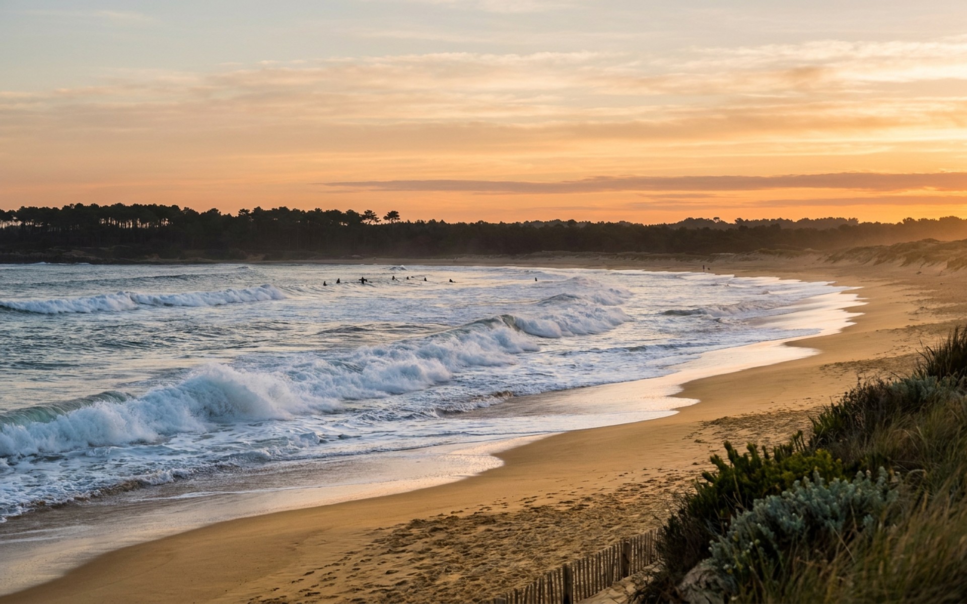Powerful Atlantic Ocean waves crashing onto a wide sandy beach, with a distant pine forest line and surfers silhouetted at sunset. at Hossegor & Landes, France — original Triple VIP destination visual.