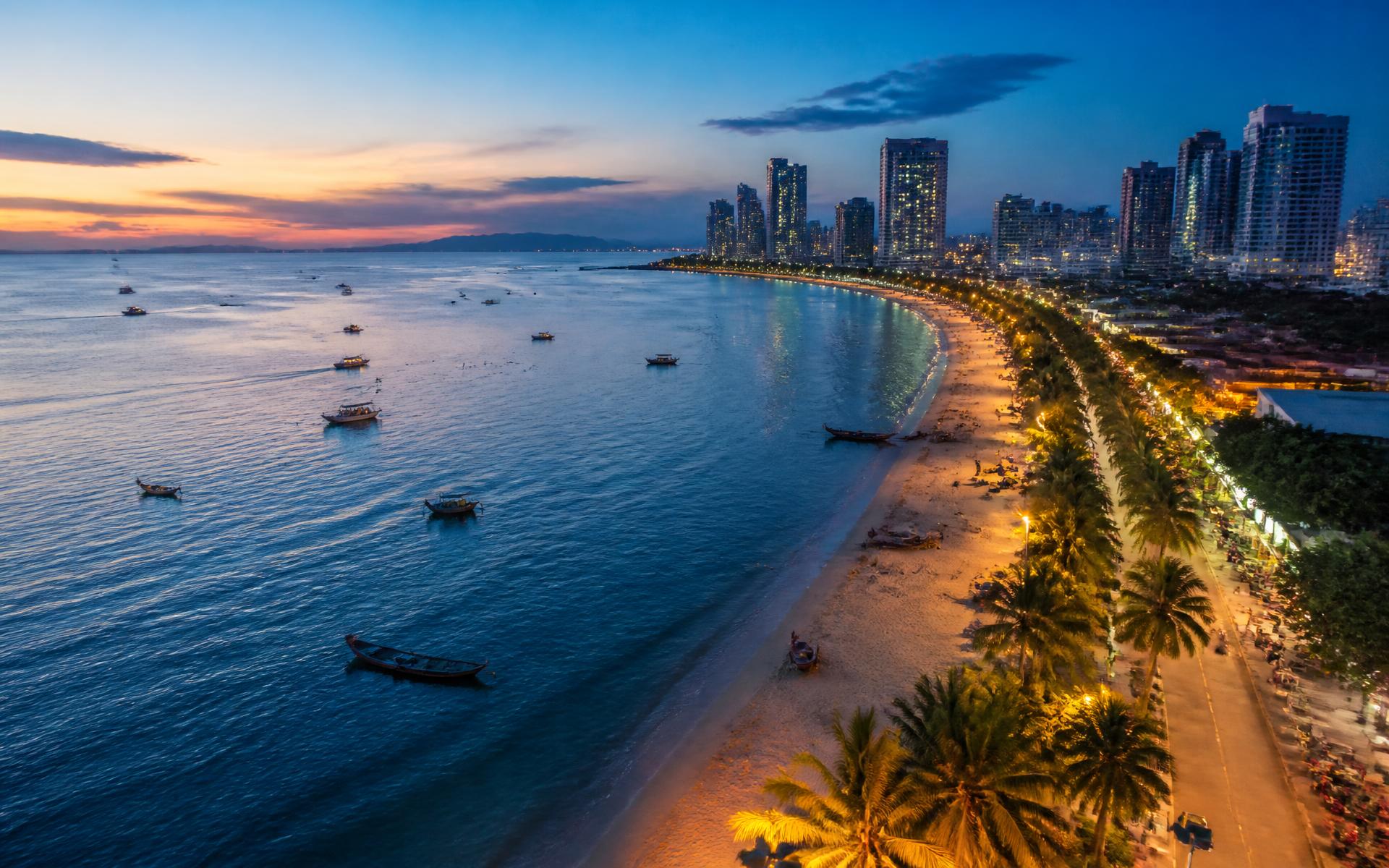 a curving city bay of high-rises and long-tail boats above calm water at dusk at Pattaya, Thailand — original Triple VIP destination visual.