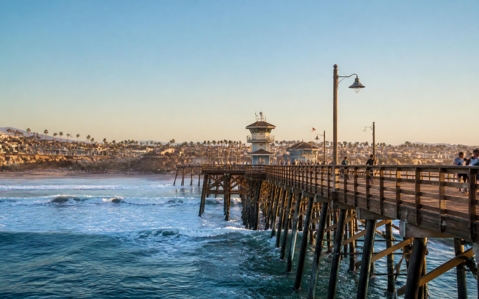 A Pacific pier and wide sand beach under warm evening light on the Orange County coast