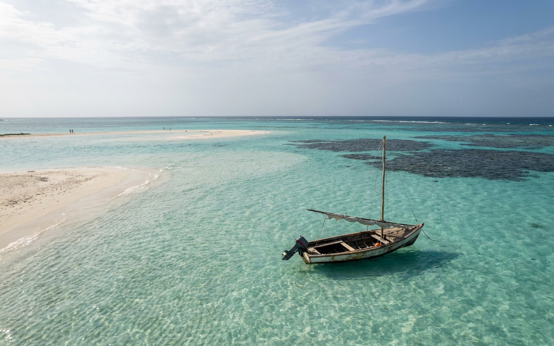 Idyllic shallow turquoise waters and white sand beaches of Los Roques archipelago, featuring a small fishing boat and distant coral reefs. at Los Roques, Venezuela — original Triple VIP destination visual.