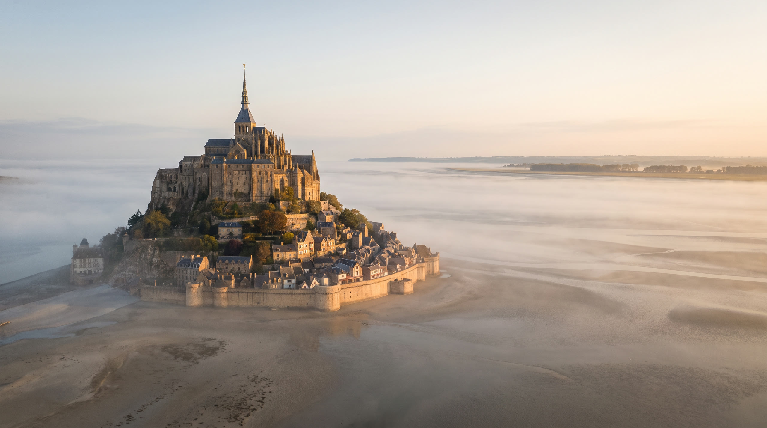 the abbey island rising from the tidal flats of the Normandy bay at Mont-Saint-Michel, France, in sunrise light — original Triple VIP destination visual.
