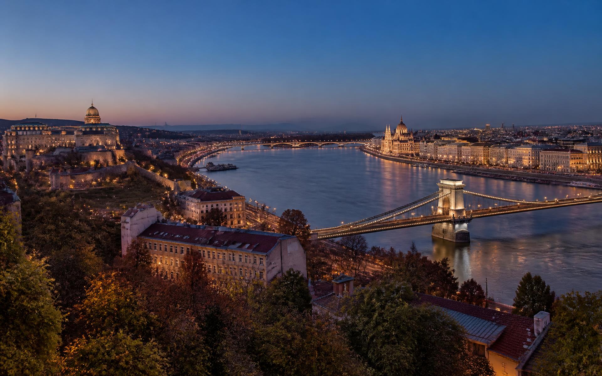 the Danube between Buda's castle hill and Pest's riverfront parliament facade at Budapest, Hungary, in blue hour light — original Triple VIP destination visual.