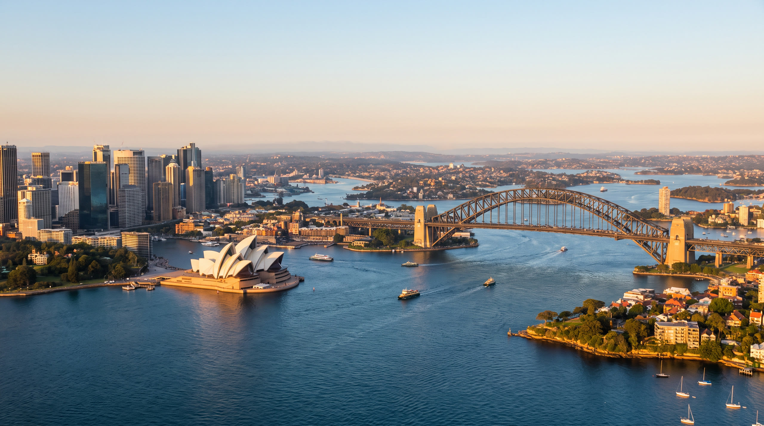 the harbour with the Opera House shells and the steel arch bridge at Sydney, Australia, in golden hour light — original Triple VIP destination visual.