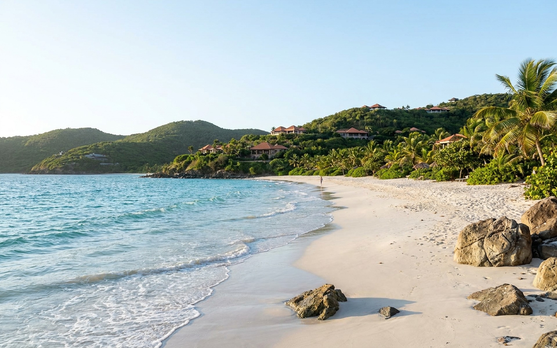 A pristine white sand beach meeting calm, cerulean Caribbean waters, with distant green hills and luxurious villas on Canouan Island. at Canouan, Saint Vincent and the Grenadines — original Triple VIP destination visual.