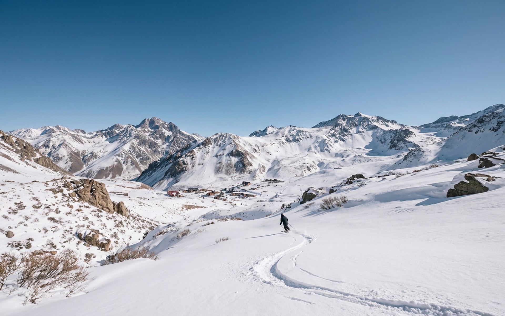 Panoramic view of snow-covered peaks and pristine ski slopes of Las Leñas, with a clear blue sky and a solitary skier making fresh tracks in winter. at Las Leñas, Argentina — original Triple VIP destination visual.