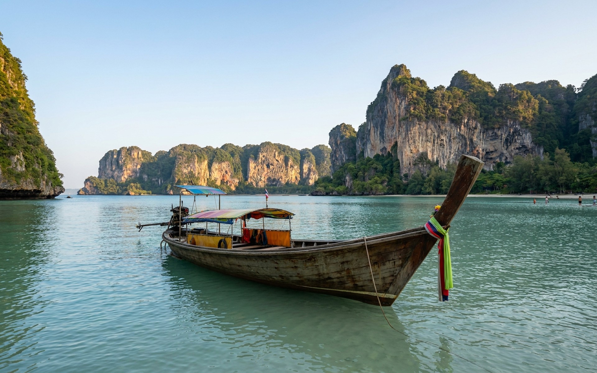 Traditional longtail boat anchored in the tranquil turquoise waters off Koh Yao Noi, with dramatic limestone karst islands rising in the background. at Koh Yao Noi, Thailand — original Triple VIP destination visual.