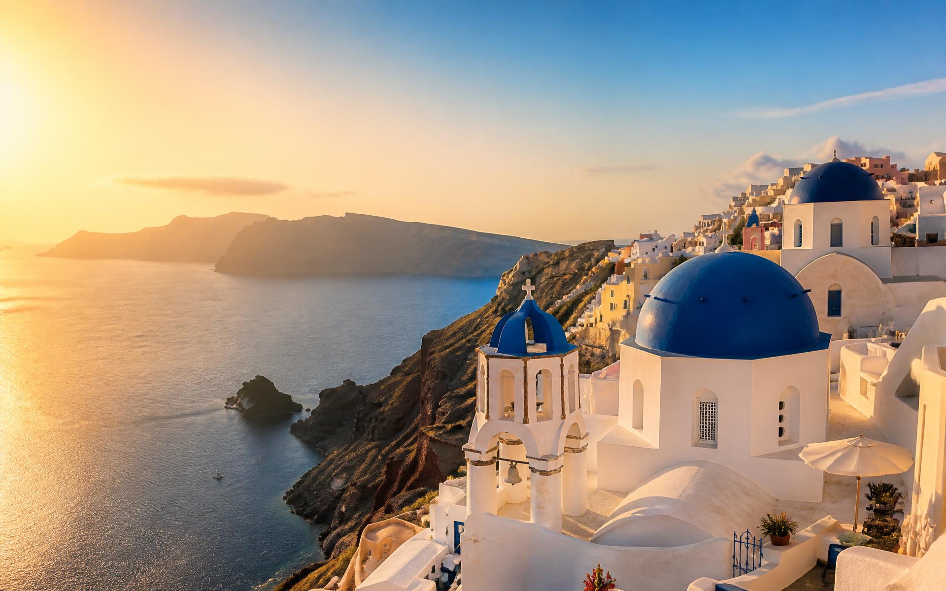 Whitewashed blue-domed churches above the Aegean caldera at sunset, Santorini, Greece