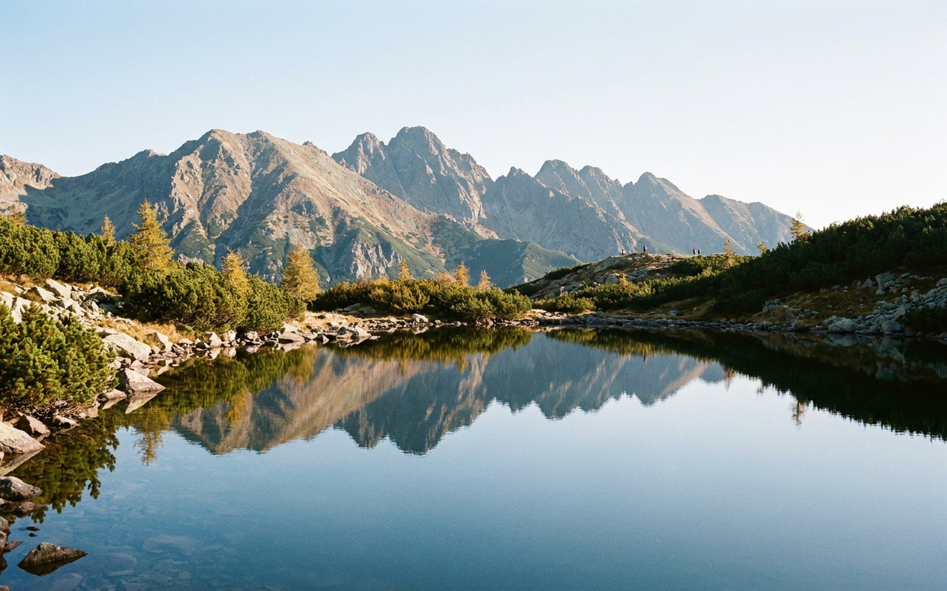granite spires above a still tarn with dwarf pine and larch in clear mountain light at the High Tatras, Slovakia — original Triple VIP destination visual.