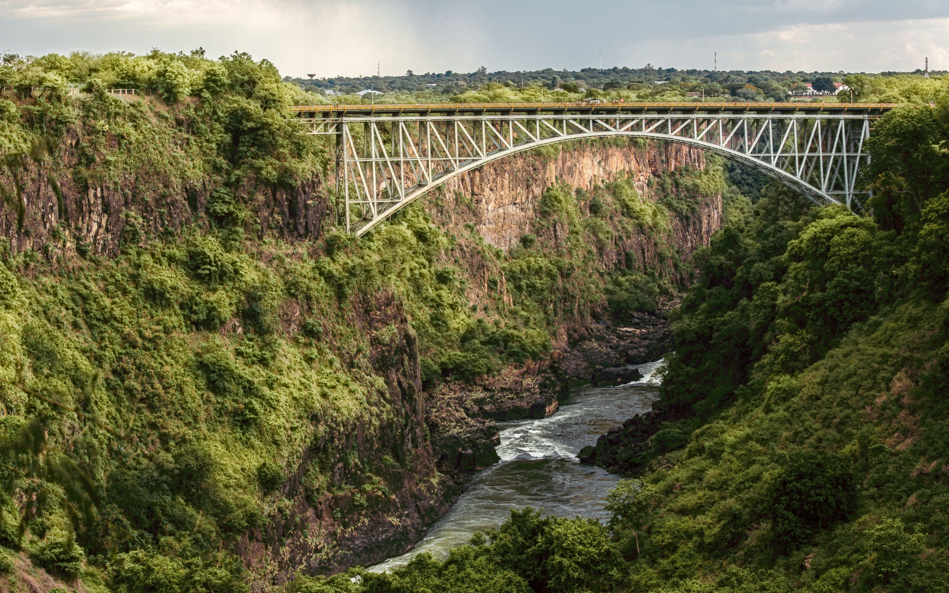 Victoria Falls Bridge gracefully arcs over the lush Batoka Gorge in Zimbabwe, showcasing stunning natural beauty.