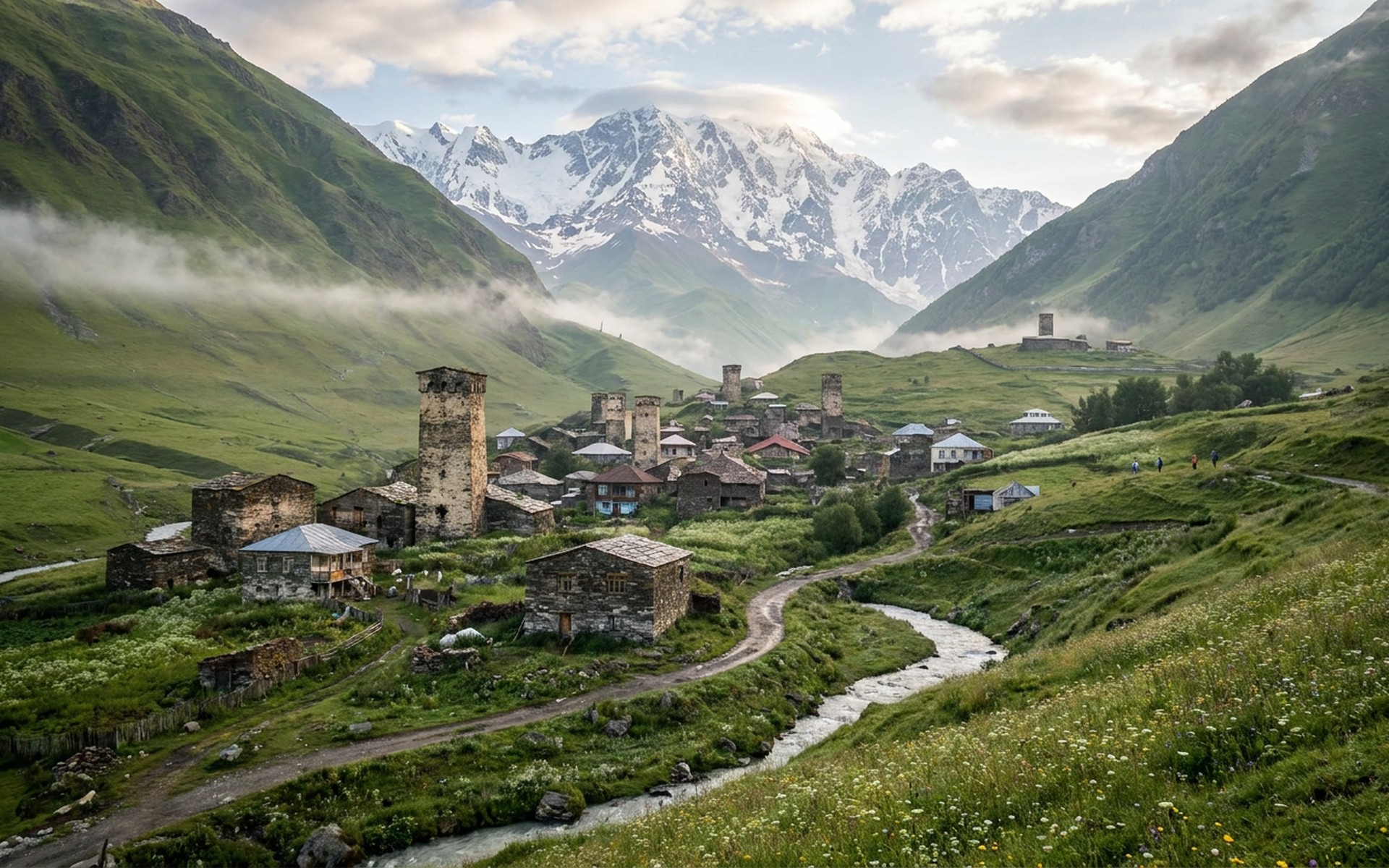 medieval stone defensive towers in a green alpine village beneath glaciated snow peaks at Svaneti, Georgia — original Triple VIP destination visual.
